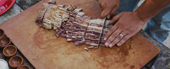 Porter-Road Old man cuts bacon a slip on a wooden board